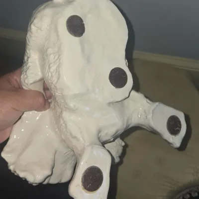 Sale Photo Thumbnail #518: Underside of a white glazed ceramic animal figurine, featuring dark felt protective pads attached to the feet and base.