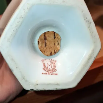 Sale Photo Thumbnail #700: Underside of a vintage hand-painted Noritake porcelain shaker, showing a red Morimura 'M' in wreath mark and original cork stopper.