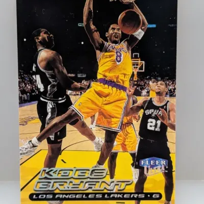 Sale Photo Thumbnail #517: Kobe Bryant 1999-00 Fleer Ultra basketball trading card featuring him dunking in a Los Angeles Lakers uniform.