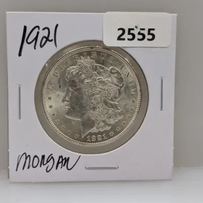 Sale Photo Thumbnail #880: 1921 Morgan silver dollar coin housed in a protective paper flip holder.