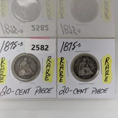 Sale Photo Thumbnail #907: Two 1875-S Seated Liberty 20-cent silver coins, individually housed in cardboard flip holders labeled with handwritten descriptions.