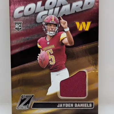 Sale Photo Thumbnail #108: Panini Zenith Football Jayden Daniels 'Color Guard' rookie jersey memorabilia card featuring a burgundy jersey swatch.