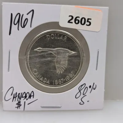 Sale Photo Thumbnail #930: 1967 Canadian silver dollar featuring the flying Canada goose Centennial motif, housed in a protective coin flip.