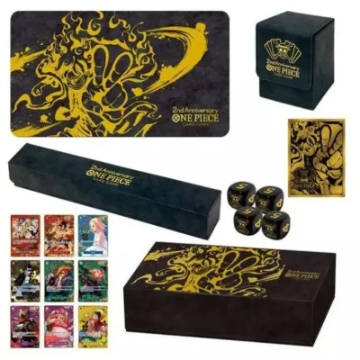 Sale Photo Thumbnail #18: One Piece Card Game 2nd Anniversary set including a playmat, deck box, storage box, sleeves, dice, and promotional cards, featuring gold Luffy artwork on a dark background.