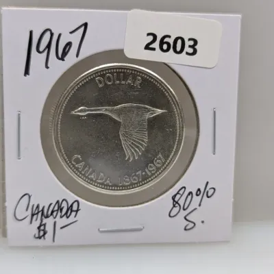 Sale Photo Thumbnail #928: 1967 Canadian silver dollar commemorating Canada's centennial, featuring a Canada goose in flight, housed in a cardboard coin flip.