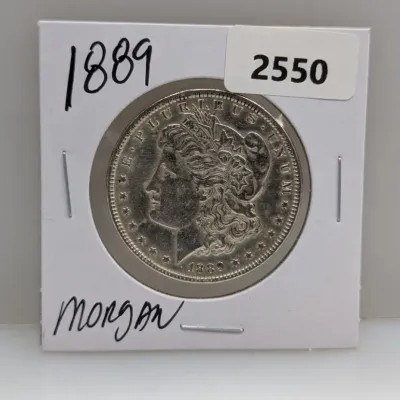 Sale Photo Thumbnail #875: 1889 Morgan silver dollar presented in a cardboard coin flip, marked with lot number 2550.