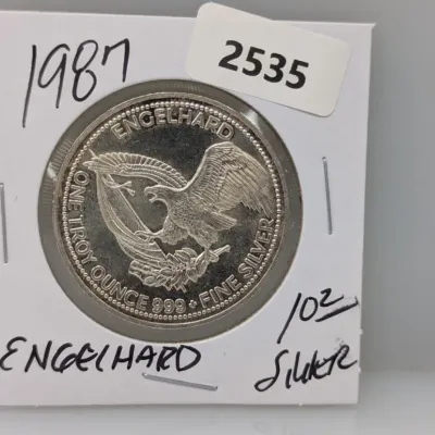 Sale Photo Thumbnail #860: 1987 Engelhard one troy ounce .999 fine silver round featuring an American eagle design, housed in a cardboard flip holder.