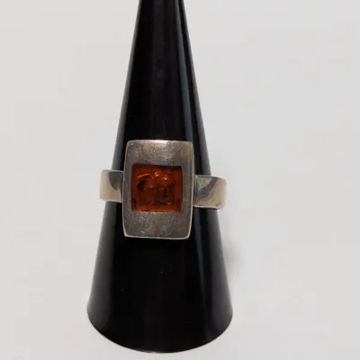 Sale Photo Thumbnail #794: Modernist sterling silver ring featuring a square bezel-set amber gemstone.