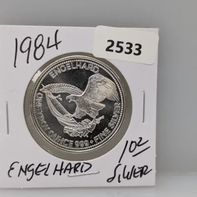Sale Photo Thumbnail #858: 1984 Engelhard 1 troy ounce .999 fine silver round featuring an American eagle design, housed in a cardboard flip.