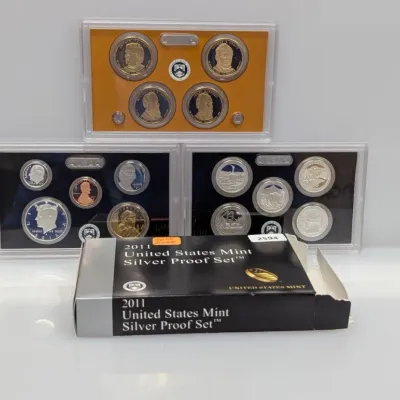 Sale Photo Thumbnail #919: 2011 United States Mint Silver Proof Set, including the Presidential $1 Coins, America the Beautiful Quarters, and standard circulating coinage in protective plastic cases with original box.
