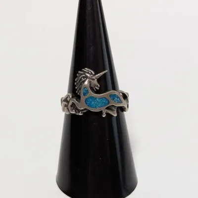 Sale Photo Thumbnail #793: Vintage sterling silver unicorn ring featuring turquoise chip inlay details, displayed on a black ring cone.
