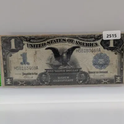 Sale Photo Thumbnail #840: Series 1899 $1 "Black Eagle" silver certificate in a protective plastic currency sleeve.