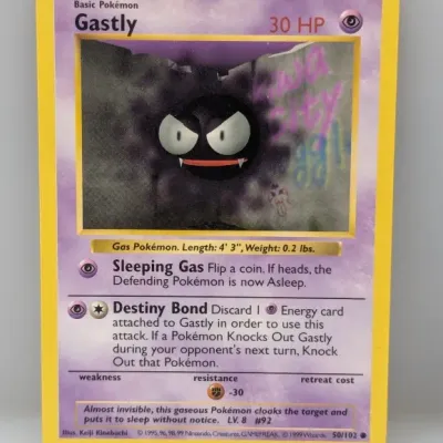 Sale Photo Thumbnail #776: 1999 Pokémon Base Set Gastly trading card (#50/102) with marker writing on the artwork window.