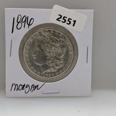 Sale Photo Thumbnail #876: 1896 Morgan silver dollar coin housed in a cardboard flip holder.