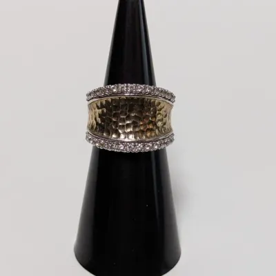 Sale Photo Thumbnail #789: Two-tone wide band ring featuring a hammered center with pave stone borders, displayed on a black ring cone.