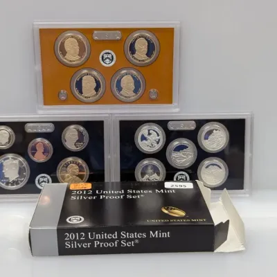 Sale Photo Thumbnail #920: 2012 United States Mint Silver Proof Set, featuring protective plastic display cases for standard proof coins, America the Beautiful quarters, and Presidential $1 coins alongside original packaging box.
