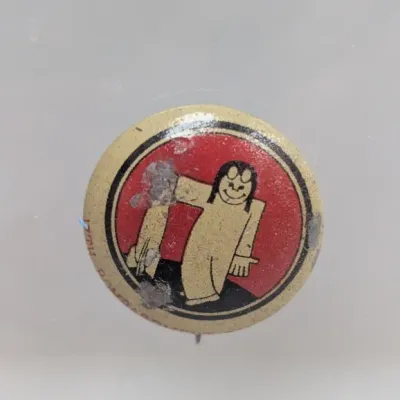 Sale Photo Thumbnail #83: Vintage pinback button featuring a stylized cartoon character against a red circular background, showing visible surface wear and residue.