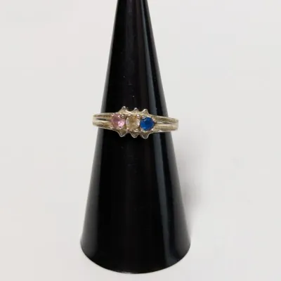 Sale Photo Thumbnail #804: Sterling silver or white gold ring featuring three round-cut birthstones in pink, light yellow, and blue, displayed on a ring cone.