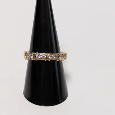 Sale Photo Thumbnail #796: Gold and diamond band with criss-cross wire detailing, displayed on a black cone stand.