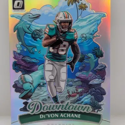 Sale Photo Thumbnail #323: 2023 Donruss Optic De'Von Achane Downtown insert trading card featuring a holofoil finish and Miami Dolphins-themed artwork.