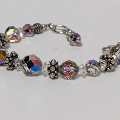 Sale Photo Thumbnail #819: Faceted aurora borealis crystal beaded bracelet with ornate silver-tone spacers and lobster claw clasp.