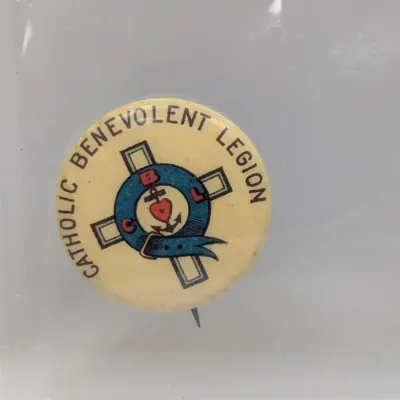 Sale Photo Thumbnail #99: Vintage Catholic Benevolent Legion pinback button inside a protective plastic sleeve, featuring the fraternal organization's emblem on a cream background.