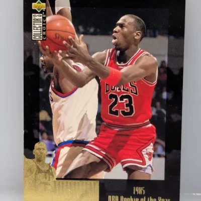 Sale Photo Thumbnail #522: 1997-98 Upper Deck Collector's Choice Michael Jordan 1985 NBA Rookie of the Year trading card, number 382. Features gold foil detailing on a black border.