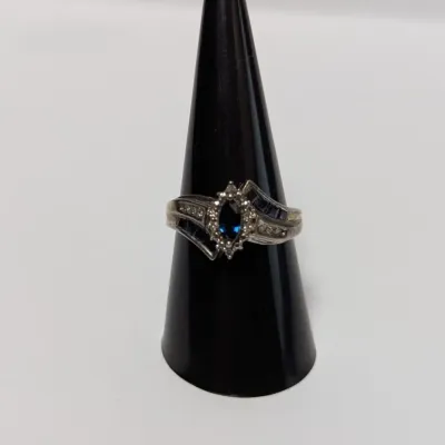 Sale Photo Thumbnail #787: Vintage sterling silver ring featuring a marquise-cut faux sapphire center stone framed by a halo of clear accents and channel-set blue baguette stones.