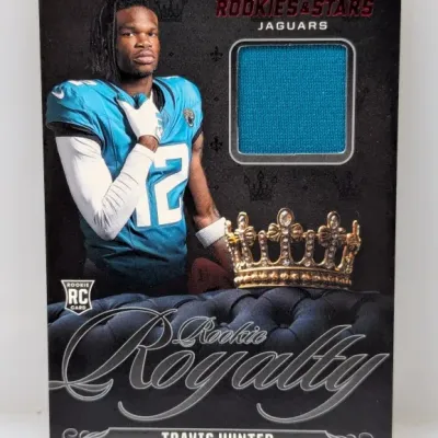 Sale Photo Thumbnail #397: Rookies & Stars Rookie Royalty Travis Hunter football card with a teal jersey relic patch.