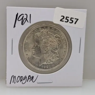Sale Photo Thumbnail #882: 1921 Morgan silver dollar, housed in a cardboard flip holder with handwritten date and label.