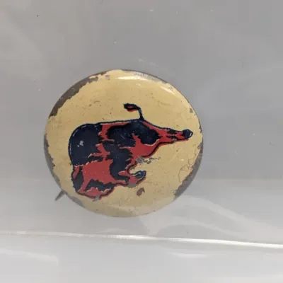 Sale Photo Thumbnail #20: Vintage pinback button featuring an illustration of a red and black animal graphic against a yellow background, enclosed in a protective sleeve.