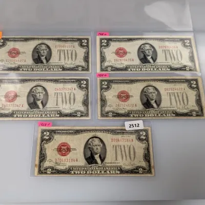 Sale Photo Thumbnail #837: Collection of five Series 1928 vintage United States two-dollar legal tender notes featuring Thomas Jefferson and red seals, each housed in protective clear sleeves.