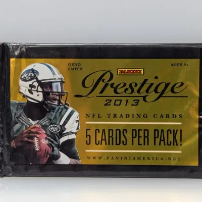 Sale Photo Thumbnail #320: Unopened 2013 Panini Prestige NFL trading card pack featuring Geno Smith on the cover, containing 5 cards.