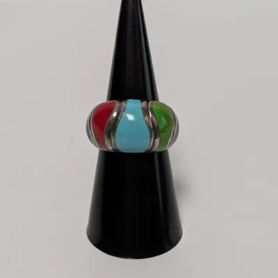 Sale Photo Thumbnail #788: Sterling silver inlay ring featuring colorful teardrop-shaped panels of turquoise, red coral, green stone, and other inlaid materials, displayed on a black ring stand.