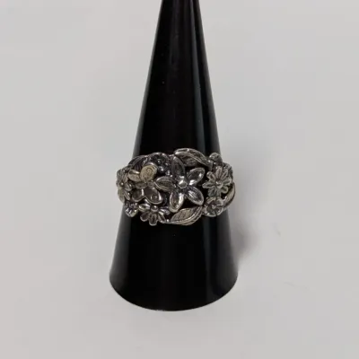 Sale Photo Thumbnail #805: Sterling silver floral band ring with intricate flower and leaf detailing, displayed on a black ring cone.