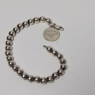 Sale Photo Thumbnail #813: Tiffany & Co. sterling silver bead bracelet featuring a signature 'Please Return to Tiffany & Co. New York 925' round charm and a lobster claw clasp.