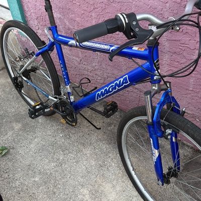 Sale Photo Thumbnail #9: Blue Magna Great Divide hardtail mountain bike with front suspension fork and padded saddle, showing minor frame wear.