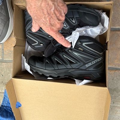 Sale Photo Thumbnail #31: Pair of Salomon Gore-Tex men's hiking boots in black and grey, displayed inside their original shoe box in gently used condition.