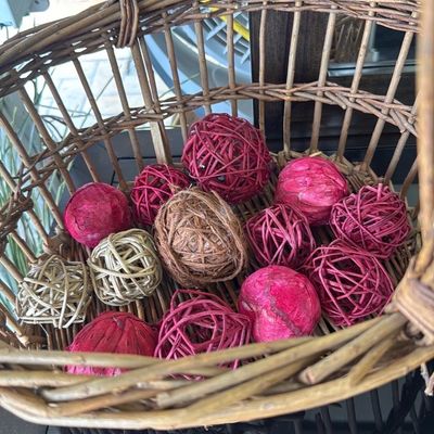 Sale Photo Thumbnail #36: Rustic woven basket filled with an assortment of pink, red, and natural-toned decorative wicker and rattan balls.