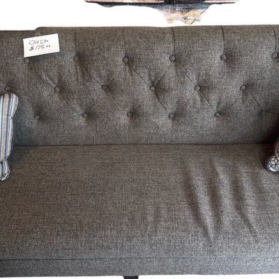 Sale Photo Thumbnail #10: Modern grey fabric sofa with a button-tufted back, shown beneath a large airplane-themed wall art piece.