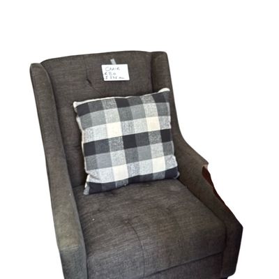 Sale Photo Thumbnail #8: Contemporary dark gray upholstered wingback armchair featuring tufted details and a black-and-white plaid accent pillow.