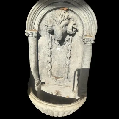 Sale Photo Thumbnail #382: Large architectural cast concrete wall-hanging fountain featuring a high-relief sculpted ram's head (Aries) centerpiece flanked by side columns and a ribbed semi-circular lower water basin.  