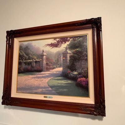 Sale Photo Thumbnail #16: Framed Thomas Kinkade style canvas print depicting a sunlit stone gate and garden path, housed in an ornate carved mahogany wood frame.