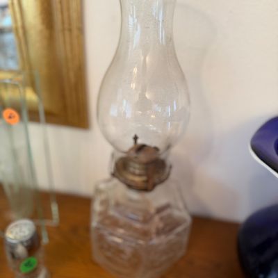 Sale Photo Thumbnail #58: Vintage clear glass oil lamp featuring a hexagonal base, aged metal burner, and a clear glass hurricane shade.