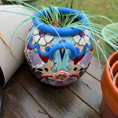 Sale Photo Thumbnail #33: Hand-painted Talavera-style ceramic planter featuring vibrant floral and geometric motifs, holding a small grassy plant.
