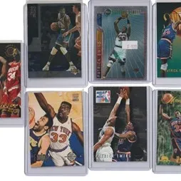 Collection of seven 1990s Patrick Ewing basketball trading cards in protective plastic sleeves.