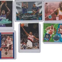 Assortment of vintage and modern NBA basketball trading cards presented in protective top loaders, including Scottie Pippen and Clyde...