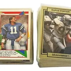 Two thick stacks of vintage football trading cards from the 1990s, including a Pacific Jeff George card and a Rufus Porter Seattle...