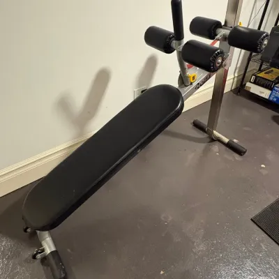 Sale Photo Thumbnail #135: Hoist Fitness adjustable decline sit-up and ab bench with black vinyl upholstery and foam leg rollers.