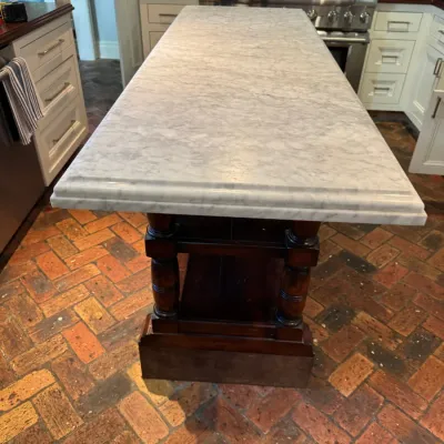 Sale Photo Thumbnail #153: Large kitchen island featuring a white-and-gray marble slab top over a dark wood base with turned posts and open lower shelving.